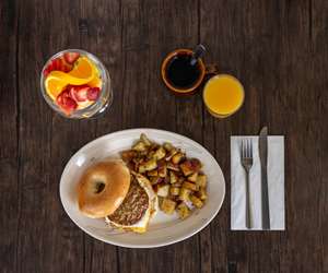 Sausage, Egg, and Cheese Sandwich on a Bagel with a Fruit Cup, Orange Juice, and Coffee